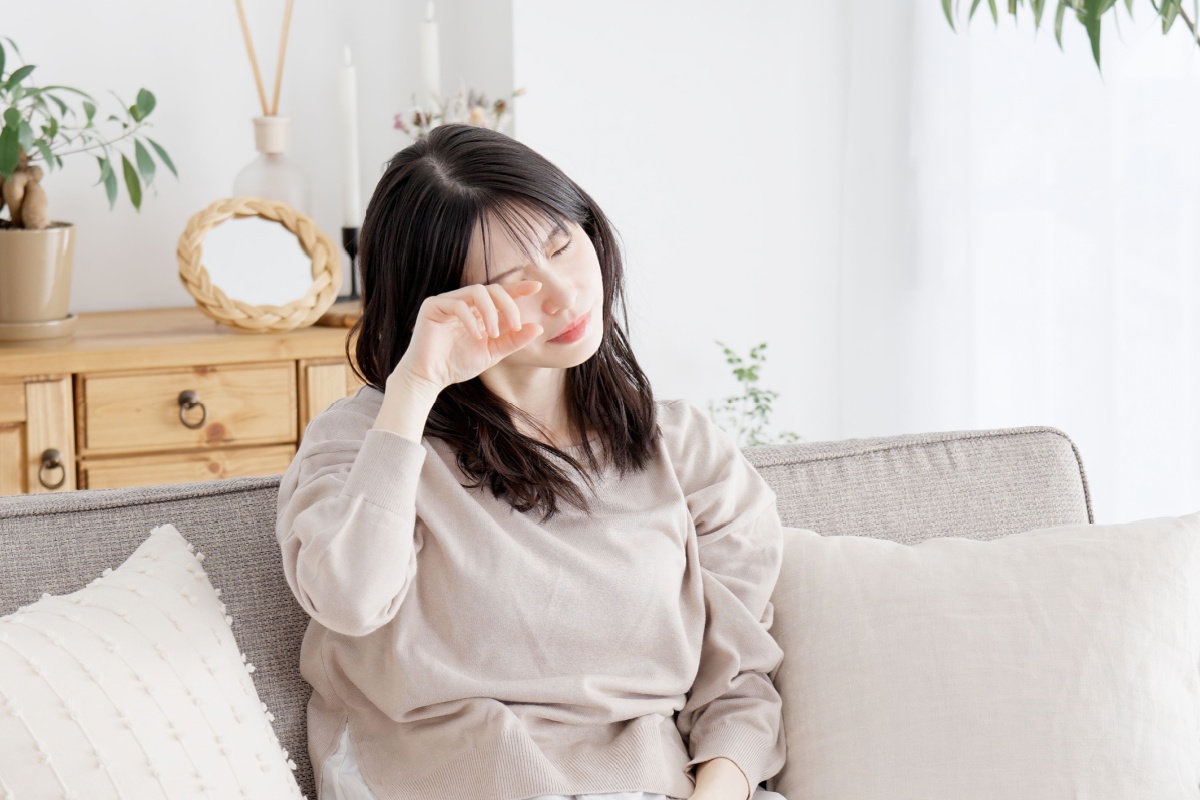 A person sitting on a couch and rubbing their dry eye